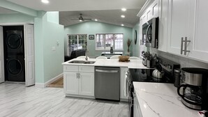 A modern kitchen with white cabinetry, a central island, and a built-in dishwasher.