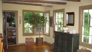 Ein geräumiger Raum mit Holzboden, einem großen Fenster, einem Schrank und einem kleinen Tisch mit einer Obstschale.
