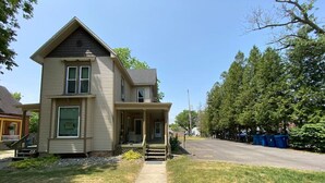 Une maison à deux étages avec un porche à l’avant et une allée.