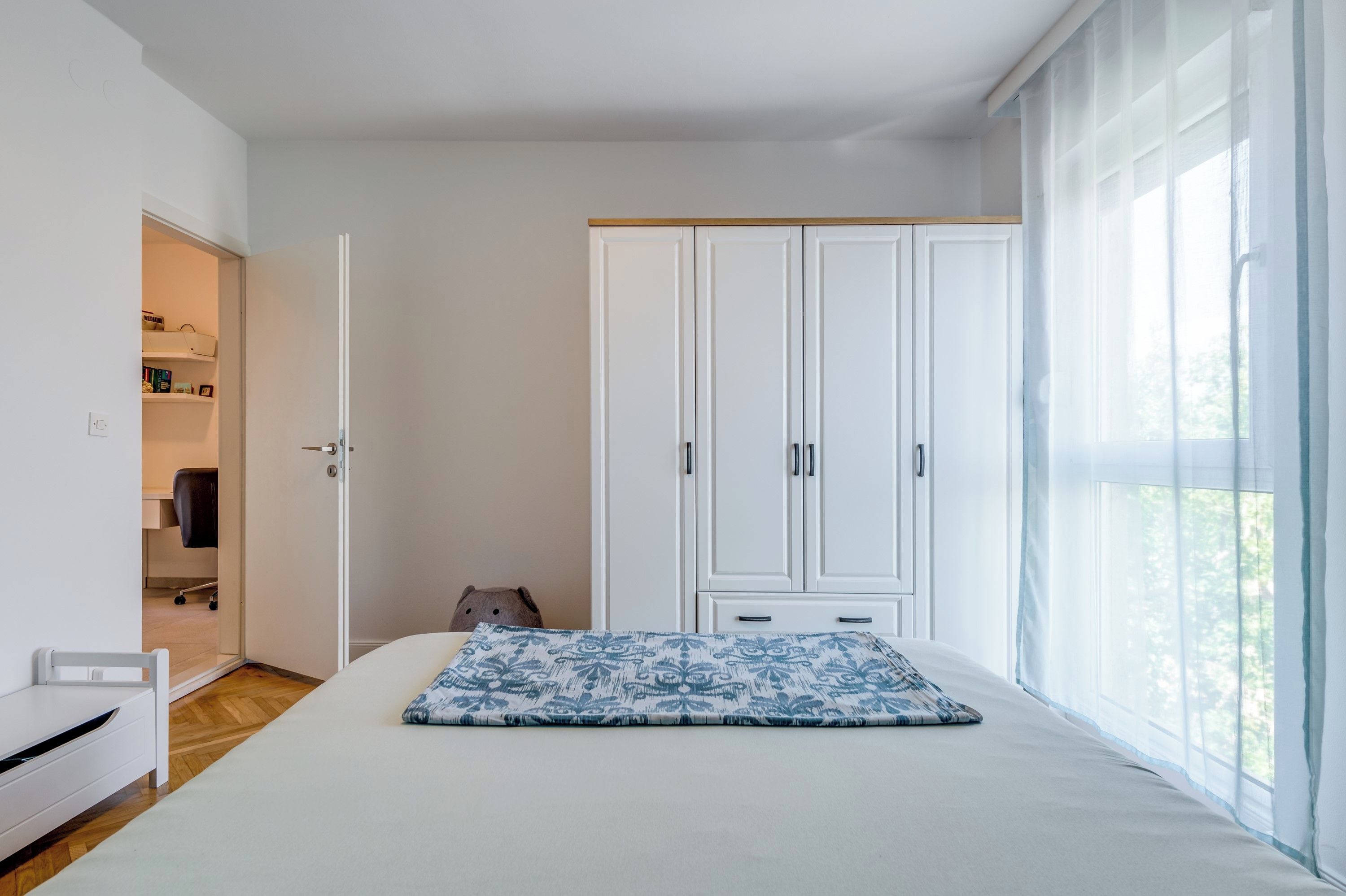 Ein Schlafzimmer mit Bett, Kleiderschrank, Schreibtisch und Stuhl.