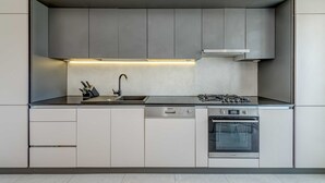A modern kitchen with a dishwasher, stove, and sink. - Modern apartment Marija with the balcony and the sea view (Split)