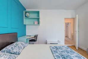 Un dormitorio con cama, escritorio, silla y estante con un globo terráqueo y un marco de fotos.