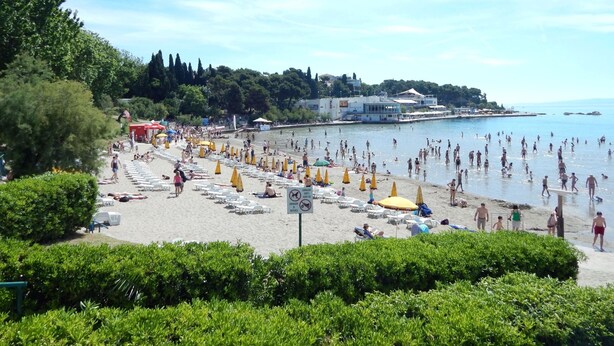 A beach with rows of sun loungers and umbrellas, a clear sky, and a building in the background. - Modern apartment Marija with the balcony and the sea view (Split)
