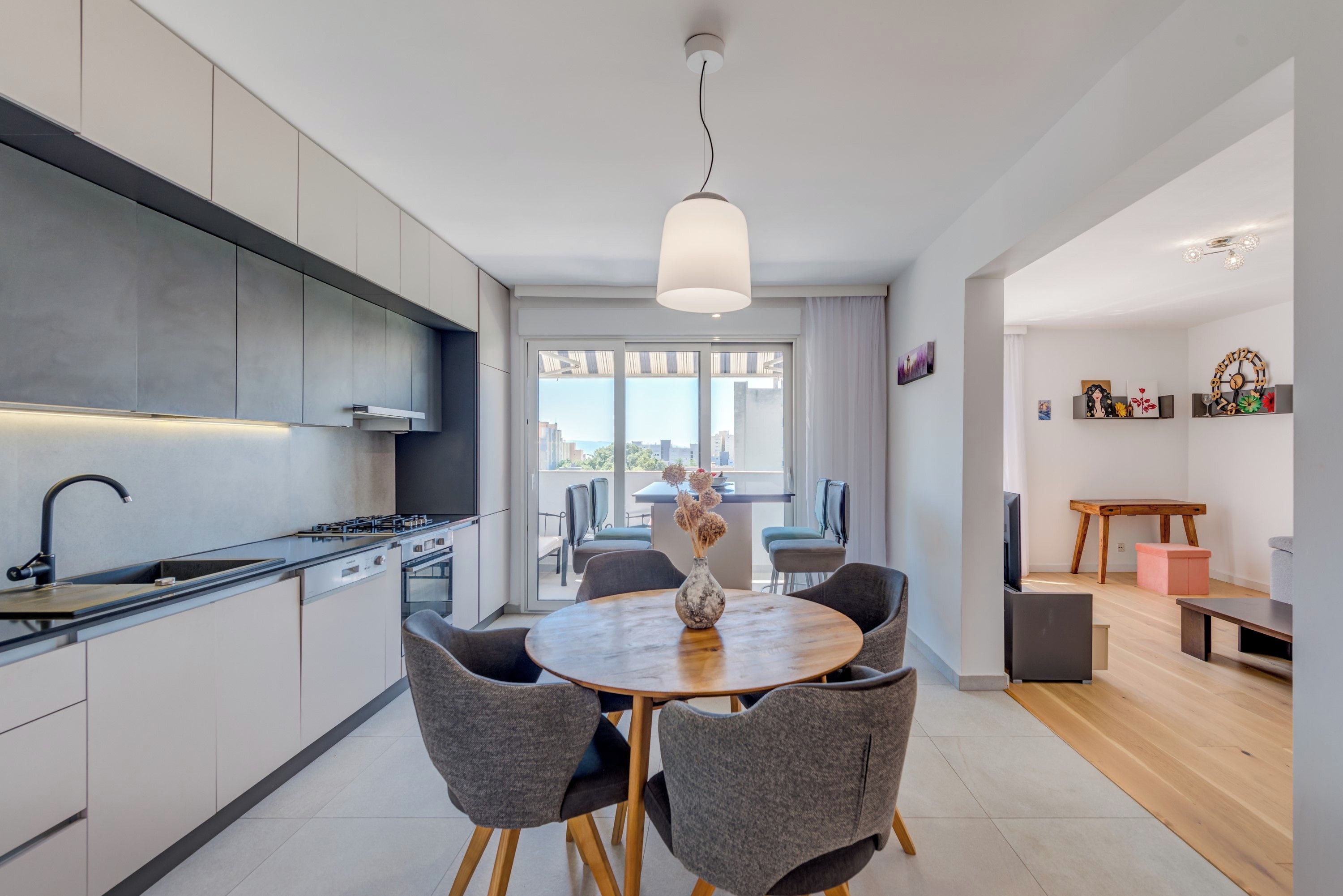 A modern kitchen with a dining area, large windows, and a view of the city.