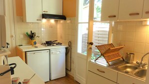 Eine kleine Küche mit Spülmaschine, Herd und einem Fenster mit Blick auf einen Garten.
