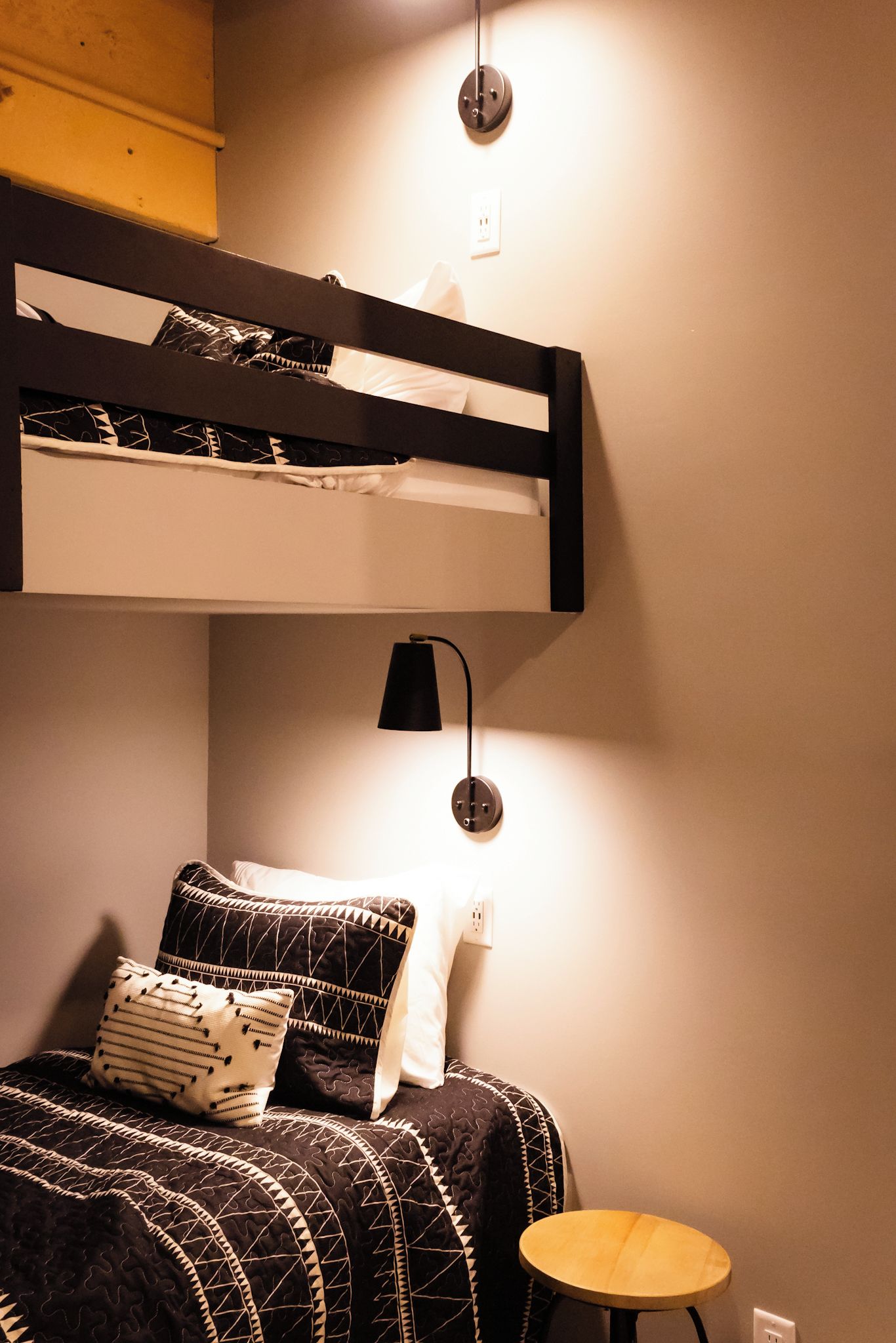 A bunk bed with a black frame, a bedside table, and a lamp.