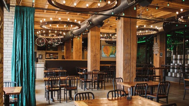 A restaurant interior with wooden tables and chairs, a bar area, and a large map on the wall. - Aurora Black | The Brix | Pool in Canal Park! (Duluth)