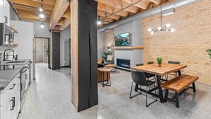 A modern kitchen with granite countertops, a black accent wall, and a dining area with a wooden table and chairs. - Aurora Black | The Brix | Pool in Canal Park! (Duluth)