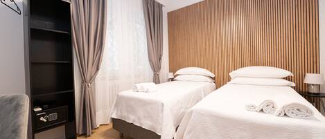 Ein Hotelzimmer mit zwei Betten, einem Kleiderschrank, einem Schreibtisch und einer Wandpaneele aus Holz.