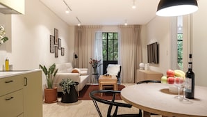 Una sala de estar moderna con un sofá, una mesa de comedor con frutas y copas de vino, un televisor y un ventanal con cortinas.