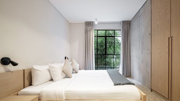 Un dormitorio moderno con una cama de madera, una mesita de noche y un ventanal con cortinas.