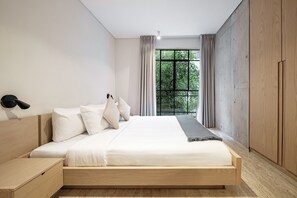 A modern bedroom with a wooden bed, a bedside table, and a large window with curtains. - Nido Condesa (Mexico City)