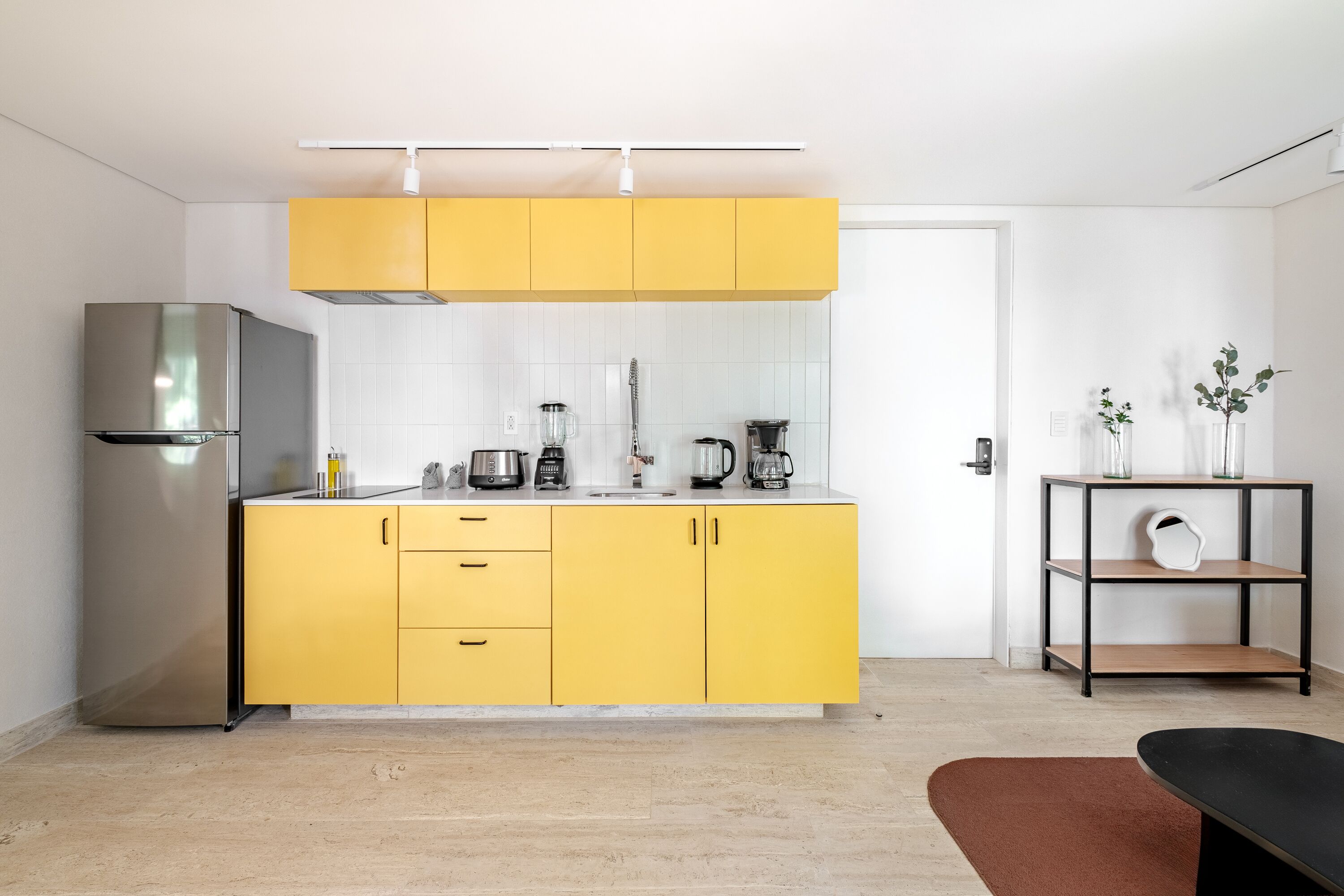 Una cocina moderna con armarios amarillos, un refrigerador de acero inoxidable y diversos electrodomésticos.