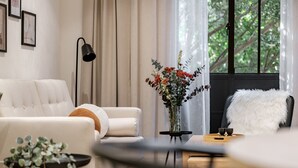 Una sala de estar moderna con un sofá blanco, una mesita de noche con un florero y una lámpara de pie negra.
