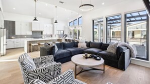 Un espacio habitable moderno con un sofá grande, un sillón estampado y una mesa de centro redonda.