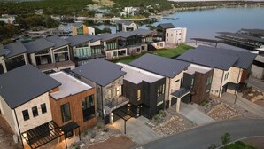 Una zona residencial moderna con casas contemporáneas, un puerto deportivo y un lago.