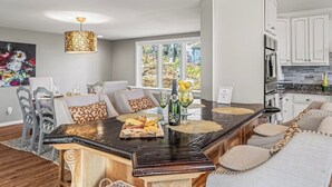 A modern kitchen with white cabinets, a central island, and a dining area with a sofa and chairs. - Hot Tub EV Charger Pool Dog OK Grill Tennis Hiking (Wintergreen Resort)