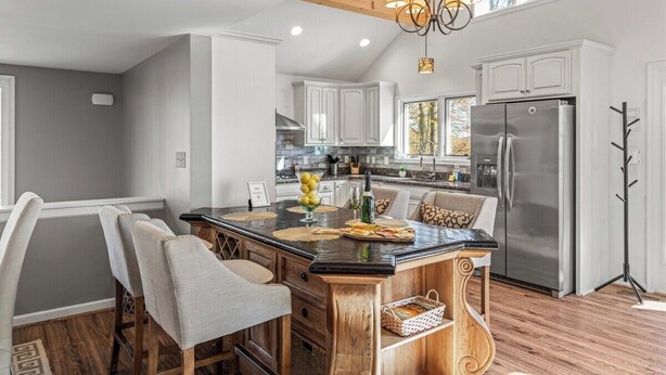 A modern kitchen with a central island, wooden chairs, a stainless steel refrigerator, and a chandelier. - Hot Tub EV Charger Pool Dog OK Grill Tennis Hiking (Wintergreen Resort)