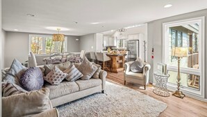 A spacious living room with a sofa, chairs, a dining table, and a kitchen in the background. - Hot Tub EV Charger Pool Dog OK Grill Tennis Hiking (Wintergreen Resort)