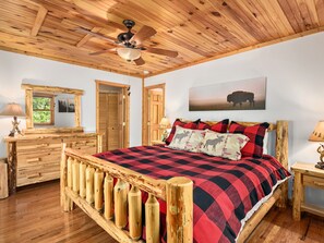 A wooden bedroom with a bed, a ceiling fan, wooden furniture, and a window.