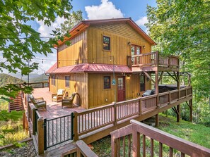 A two-story wooden cabin with a balcony, outdoor seating, and a deck.