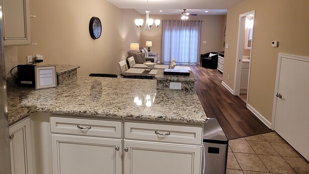 A modern kitchen with granite countertops, white cabinetry, and pendant lighting.