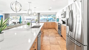 Una cocina moderna con un refrigerador de acero inoxidable, un fregadero y una isla grande.