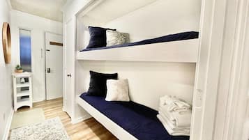 A room with a bunk bed, a small table with a plant, and a door.