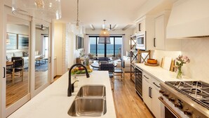 A modern kitchen with a large island, stainless steel appliances, and a view to the sea.