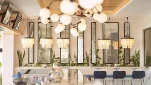 Ein modernes Interieur mit einer langen Theke, Pendelleuchten und großen Fenstern.