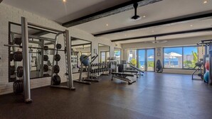 A gym with weightlifting equipment, large windows, and a view of the outdoors. - Oceanfront 2bd penthouse (San José del Cabo)