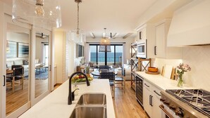 A modern kitchen with a central island, stainless steel appliances, and a view to the sea. - Oceanfront 2bd penthouse (San José del Cabo)