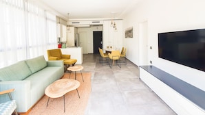 A modern living room with a sofa, coffee table, and dining area with chairs and a table. - Rupin Ruby (Tel Aviv)