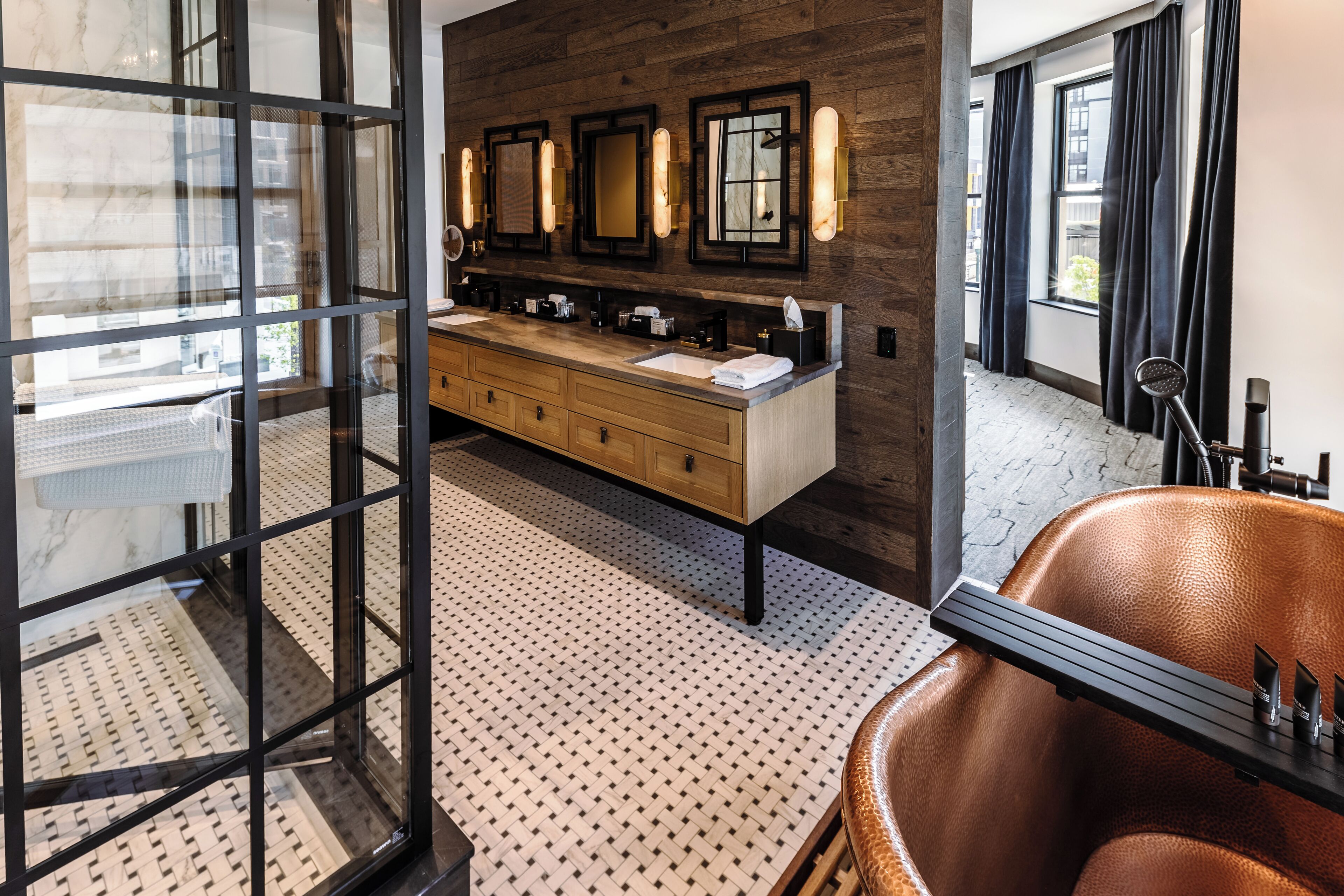 A modern bathroom with a wooden vanity, multiple mirrors, and a leather chair.