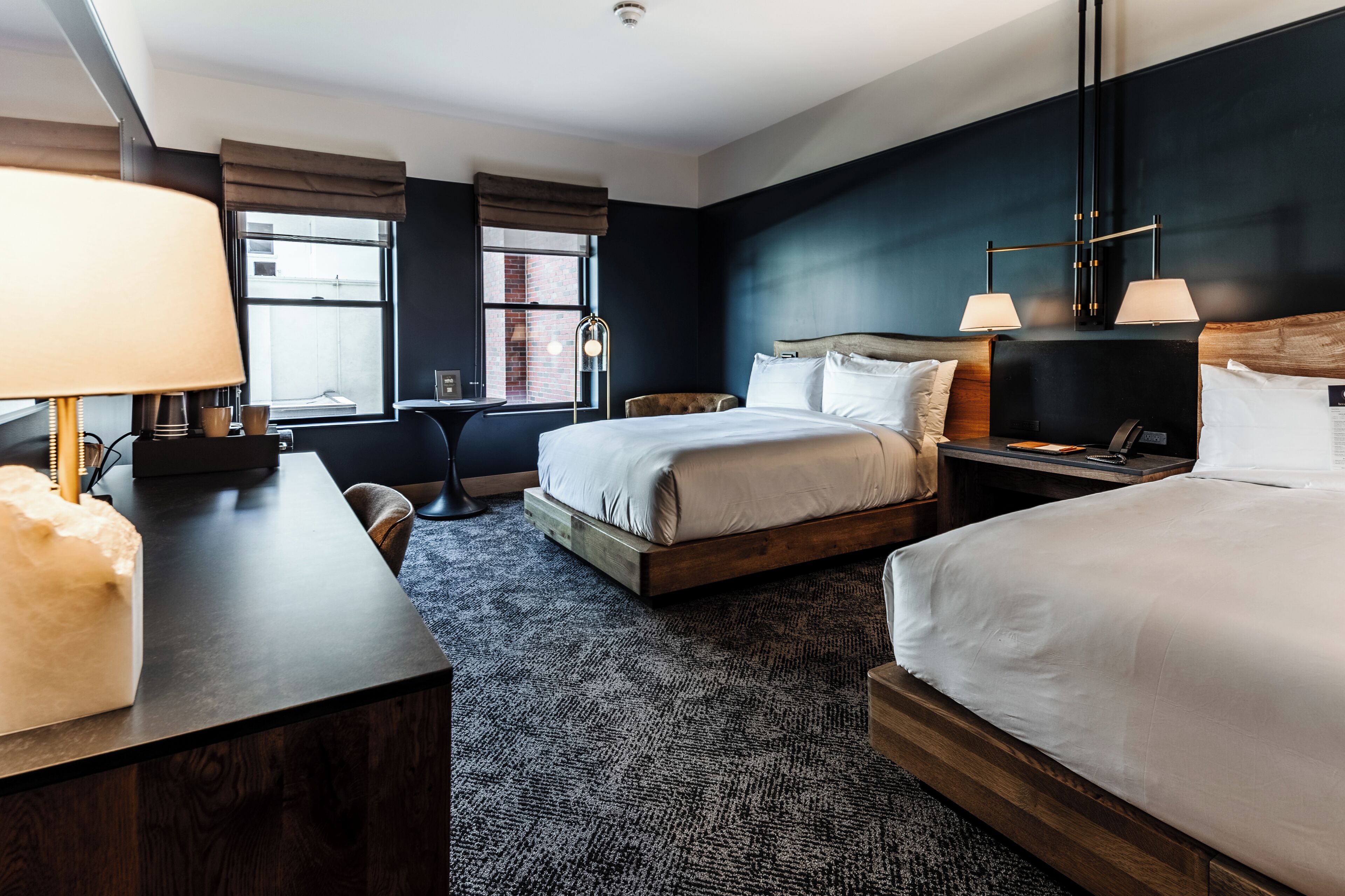 Een hotelkamer met een groot bed, een bureau met lamp, een stoel en een raam met gordijnen.