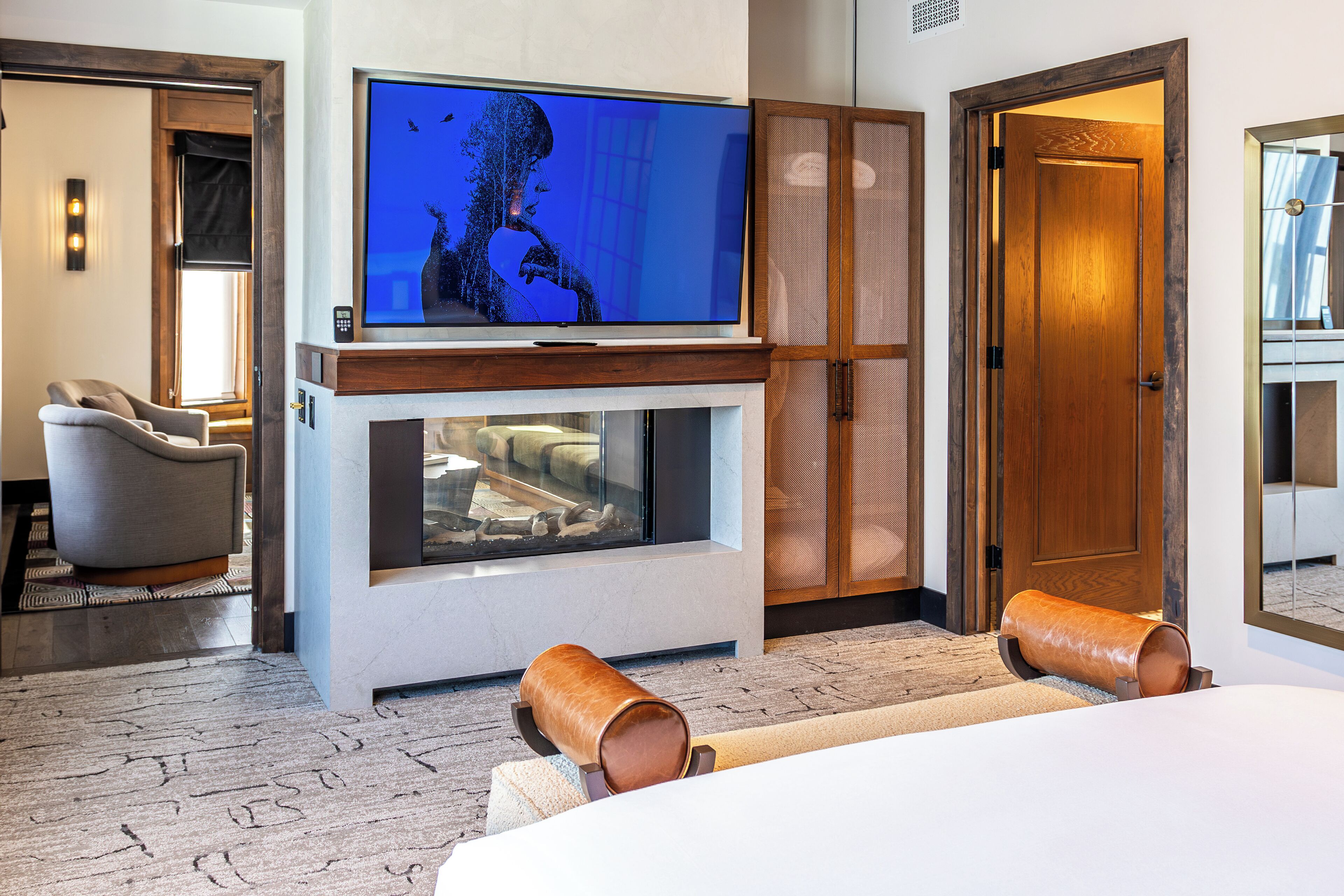 A modern hotel room with a large flat-screen TV, a comfortable sofa, and a wooden cabinet.
