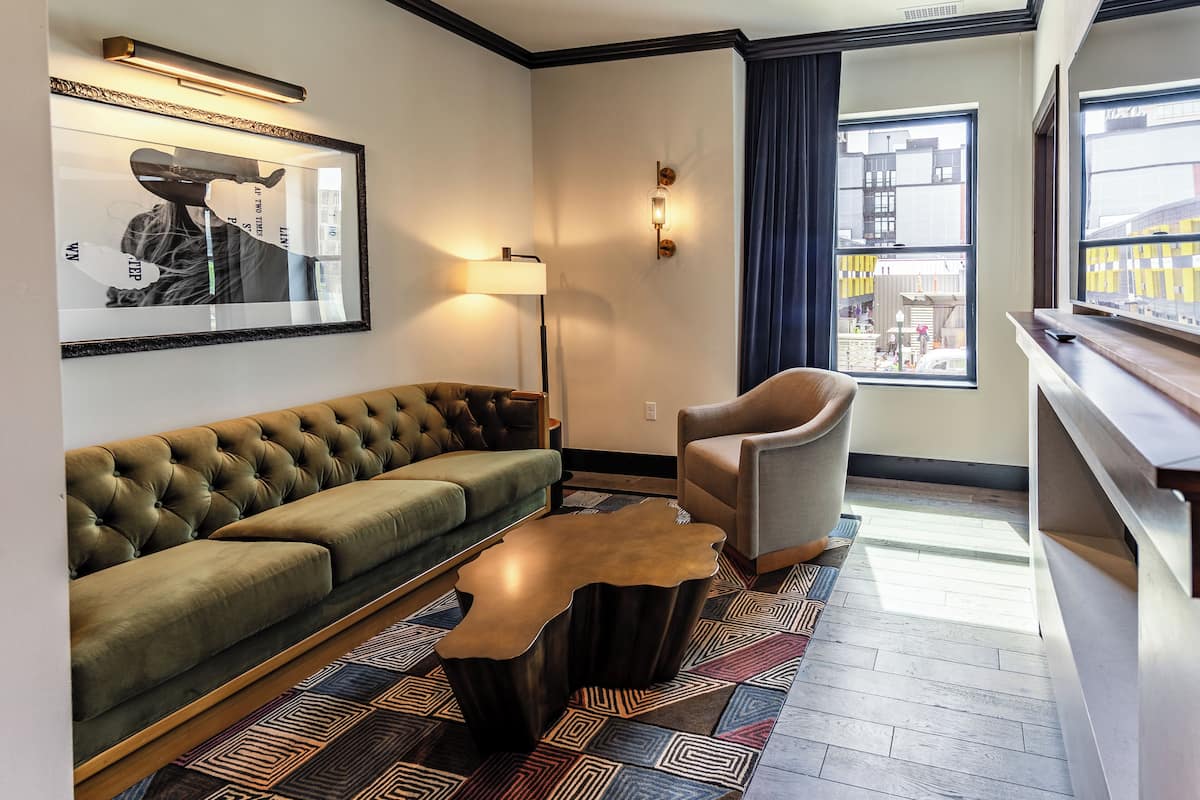 A modern living room with a tufted sofa, a leather coffee table, and a view of the city through large windows.