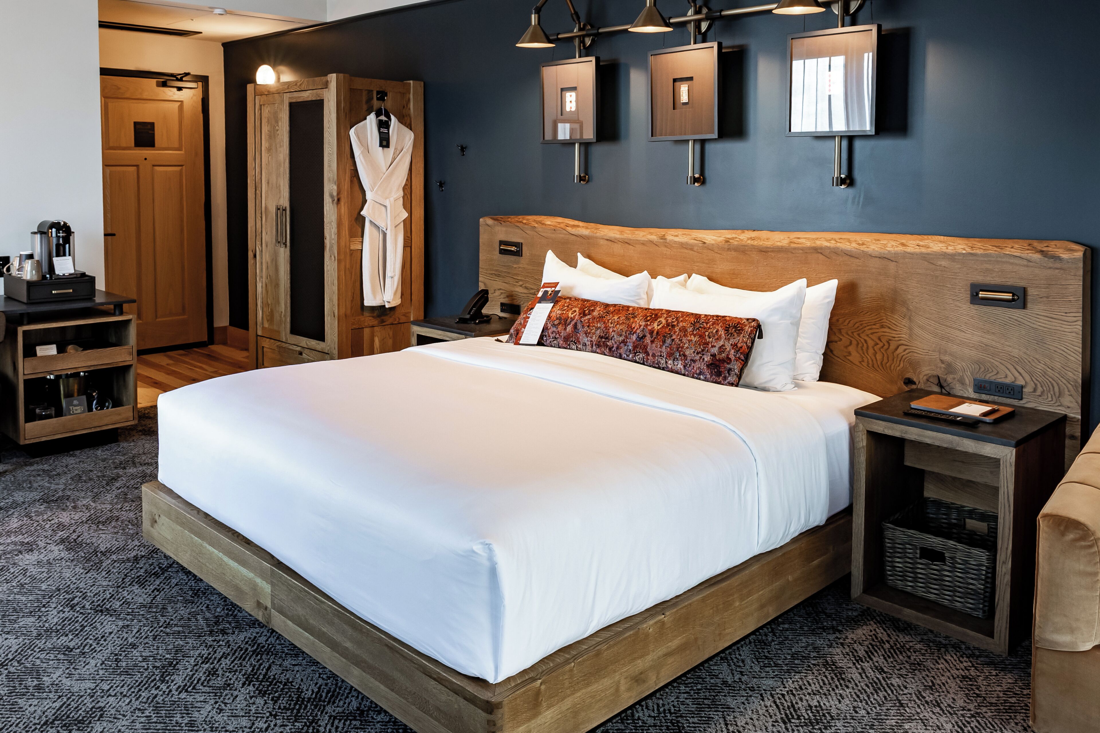 Una habitación de hotel con una cama grande, cabecero de madera, mesitas de noche, bata y televisor de pantalla plana.