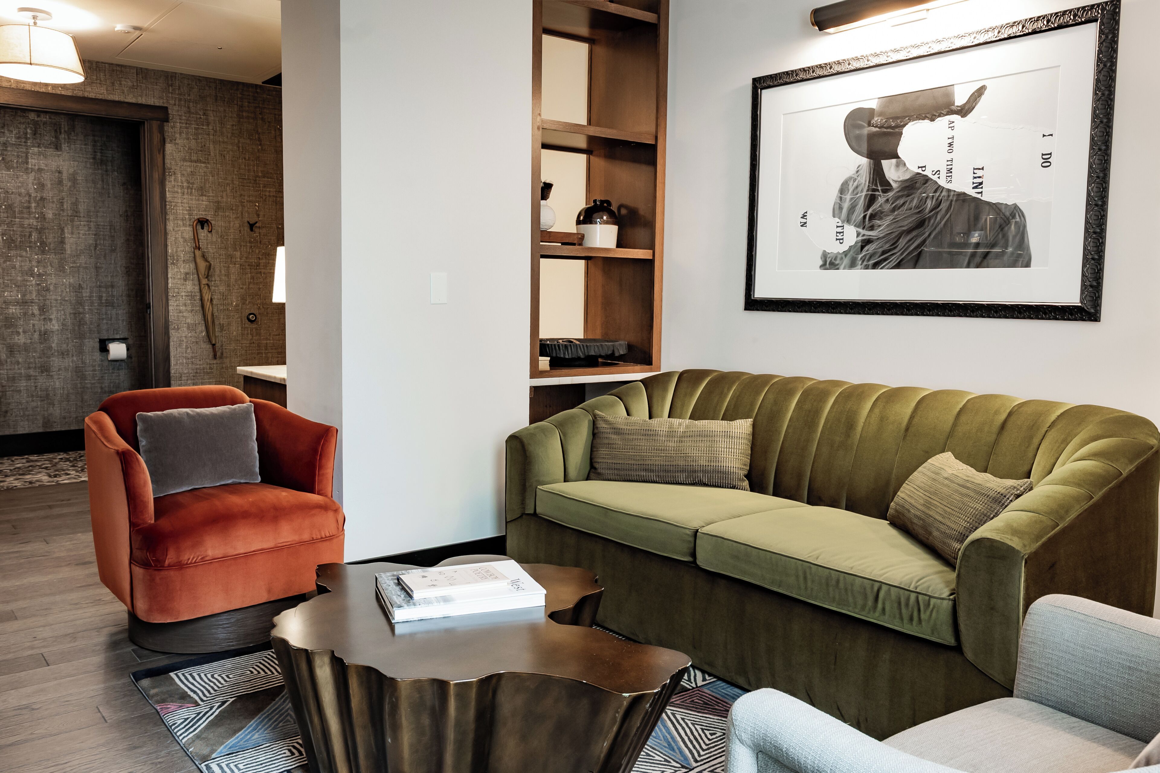 Un salon comprenant un canapé, un fauteuil, une table basse et une œuvre d’art encadrée accrochée au mur.