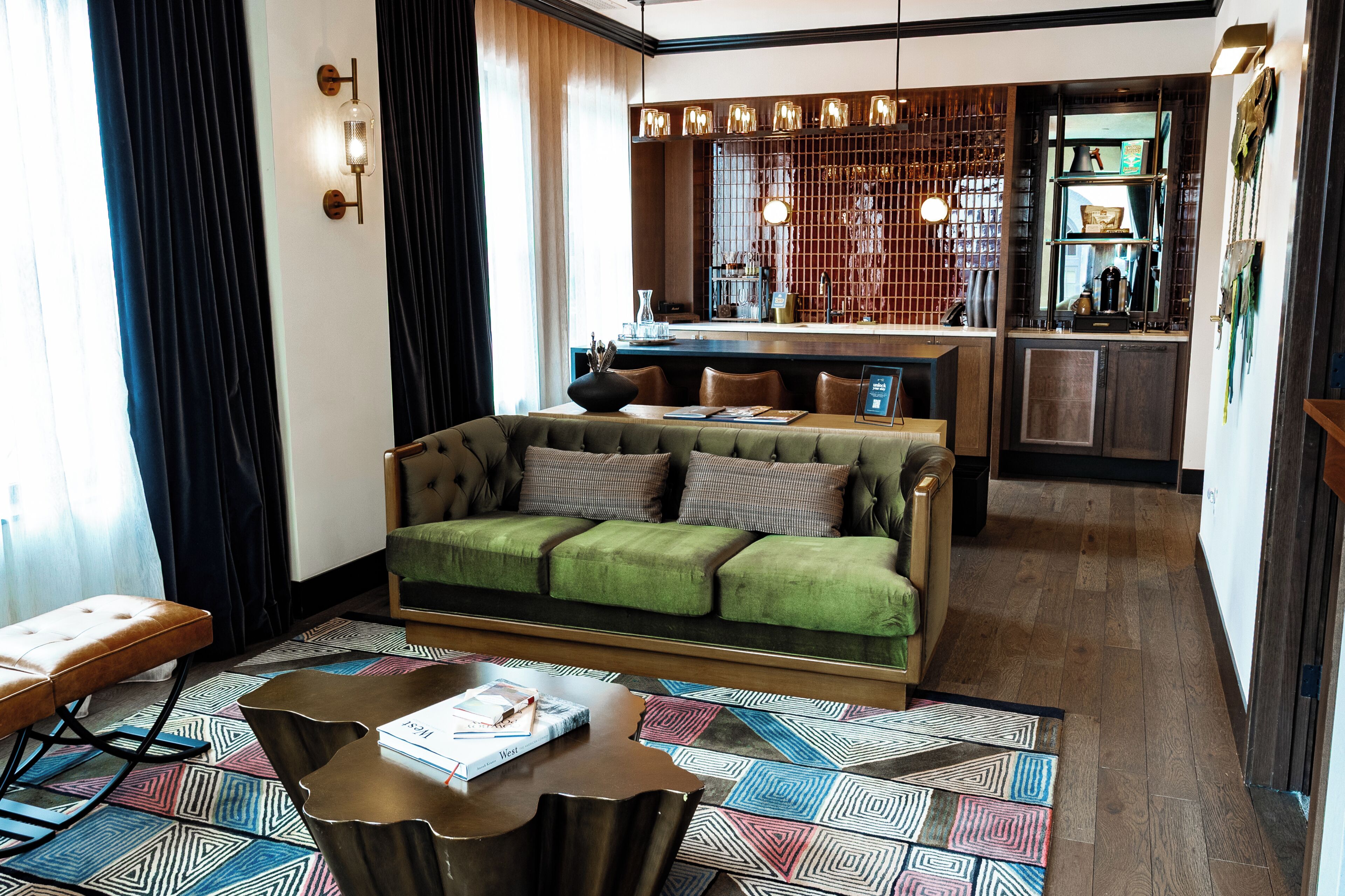 A modern living room with a green sofa, a wooden coffee table, and a patterned rug.