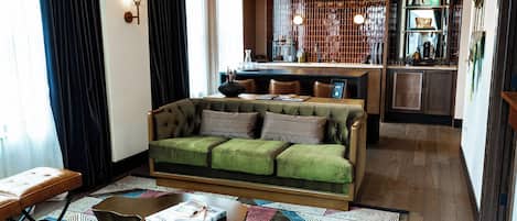 A modern living room with a green sofa, a wooden coffee table, and a patterned rug.