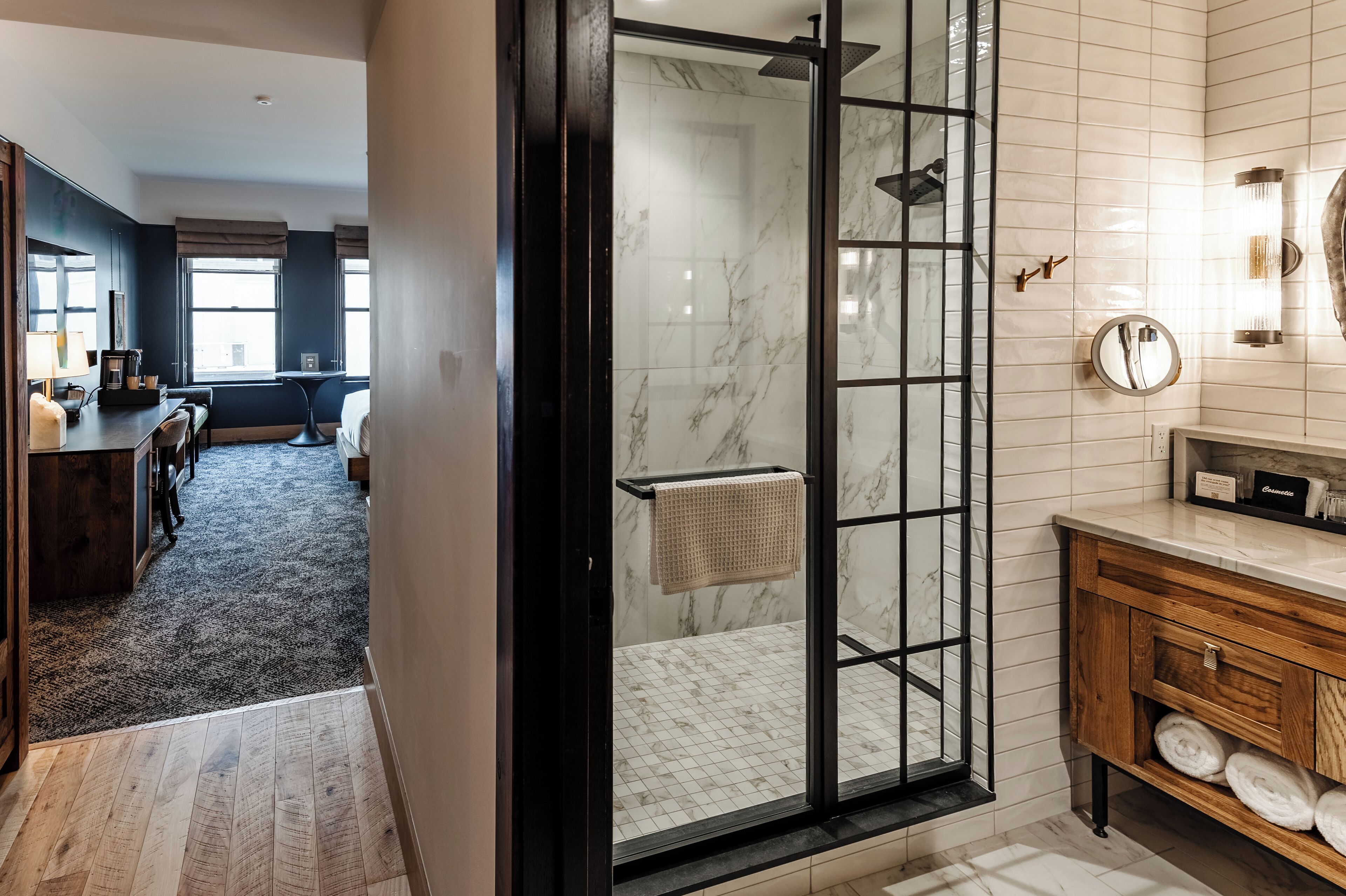 Une salle de bain moderne dotée d’une douche à parois de verre, d’un meuble-lavabo en bois et d’une zone de douche carrelée en marbre.