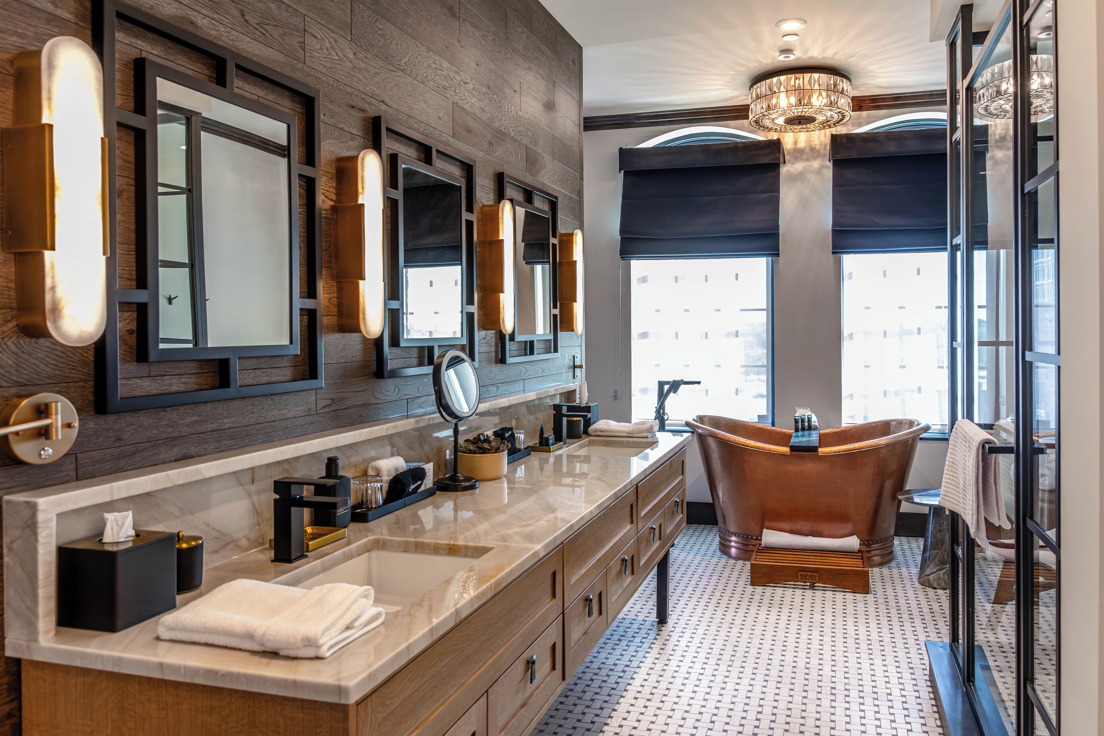 A modern bathroom with a large vanity, a freestanding bathtub, and large mirrors.