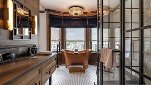 Un baño moderno con una bañera independiente, ventanas amplias y vistas a la ciudad.