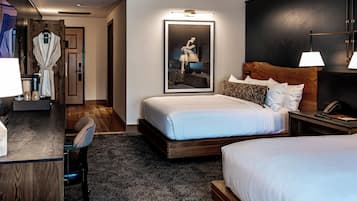 A hotel room with a large bed, a desk with a chair, a robe hanging on the door, and a framed picture on the wall.