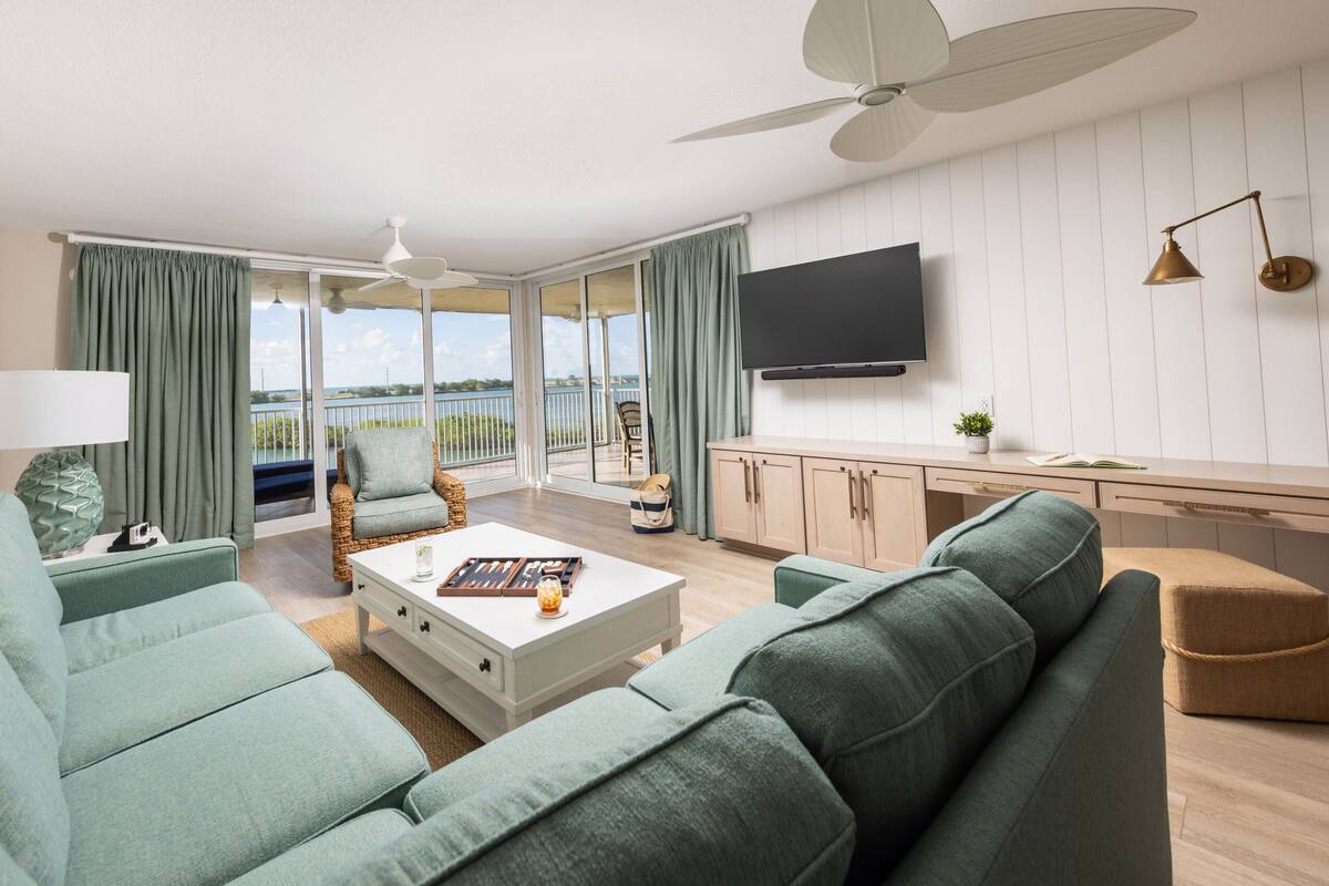 A modern living room with a sofa, coffee table, and a TV mounted on the wall.