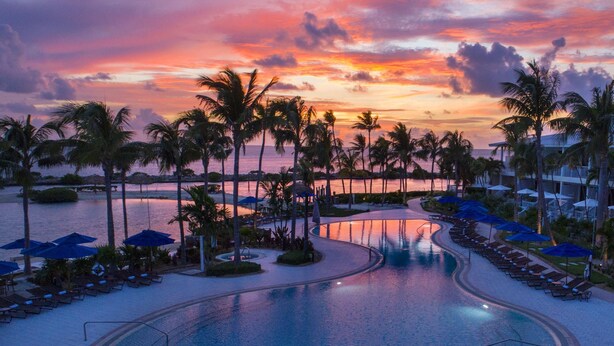 A resort pool with palm trees and lounge chairs, surrounded by a beachfront. - Villas At Hawks Cay Resort (Marathon)