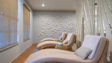 Relax in a serene spa room with lounge chairs, a patterned floor, and a large window.