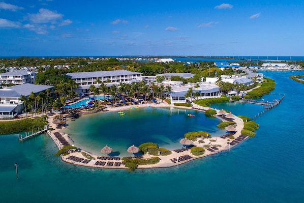An aerial view of a resort with a central pool, multiple buildings, and a marina. - Villas At Hawks Cay Resort (Marathon)
