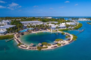 An aerial view of a resort with a central pool, multiple buildings, and a marina.